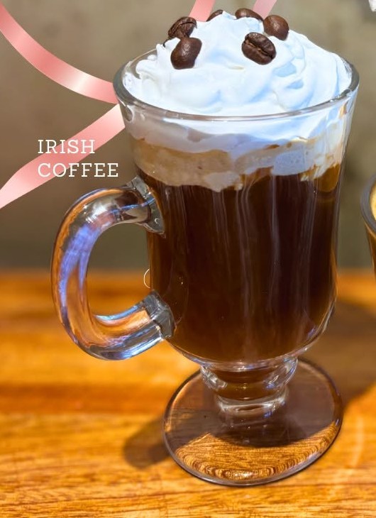 Irish coffee in a glass mug, topped with whipped cream and coffee beans.