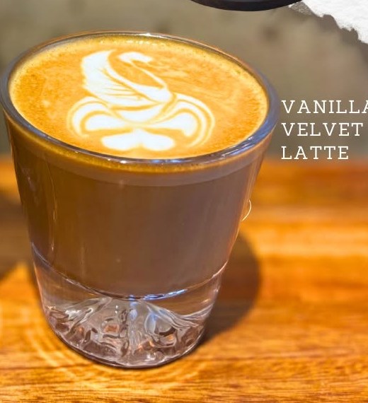 Vanilla velvet latte with swan latte art in a glass cup.